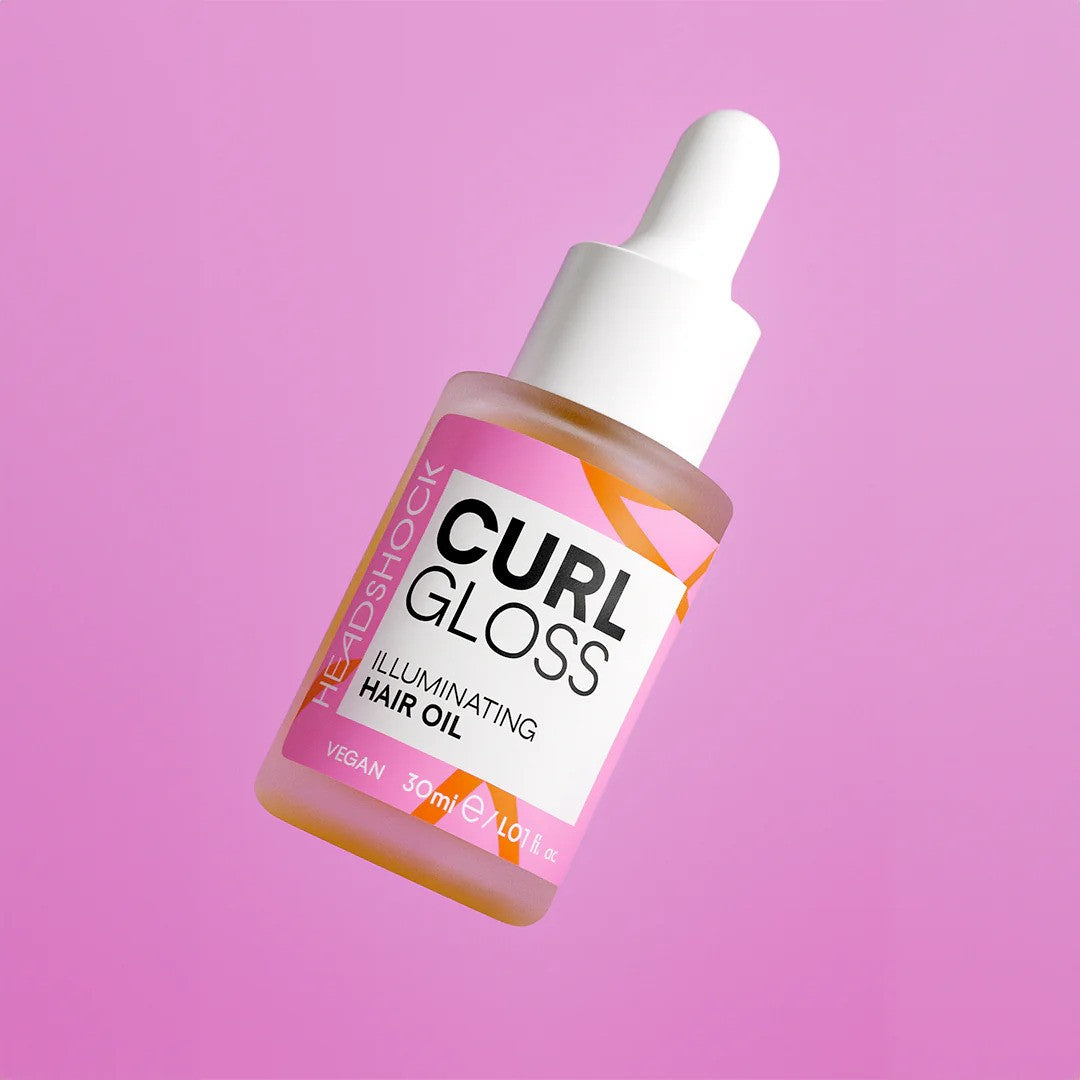 Face Facts Headshock Curl Gloss illuminating hair oil in a clear bottle with a dropper, showcasing shiny, well-defined curls.