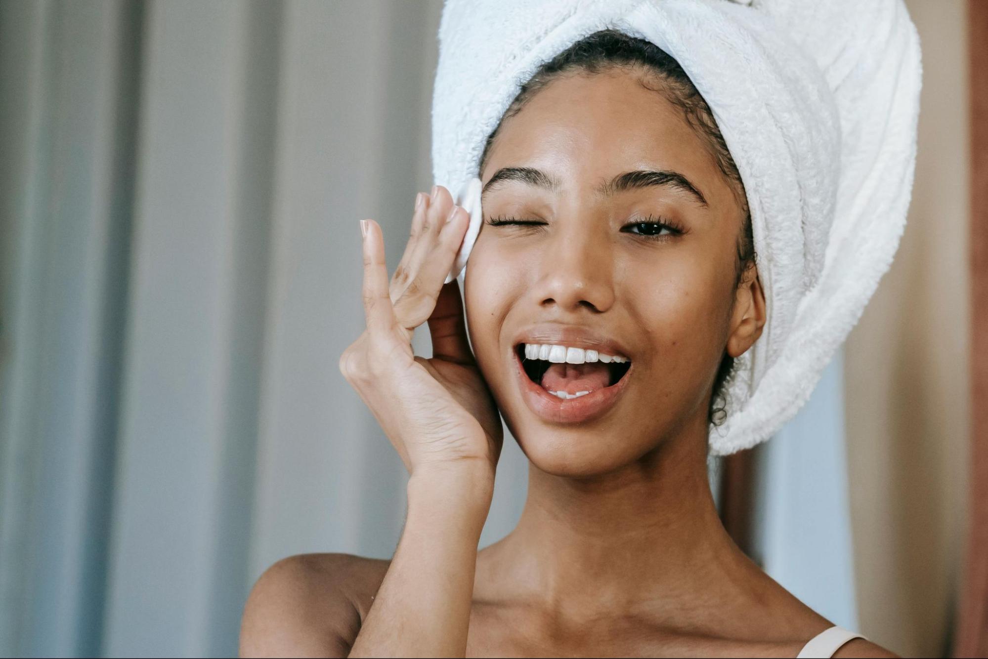 woman cleaning face with make up remover